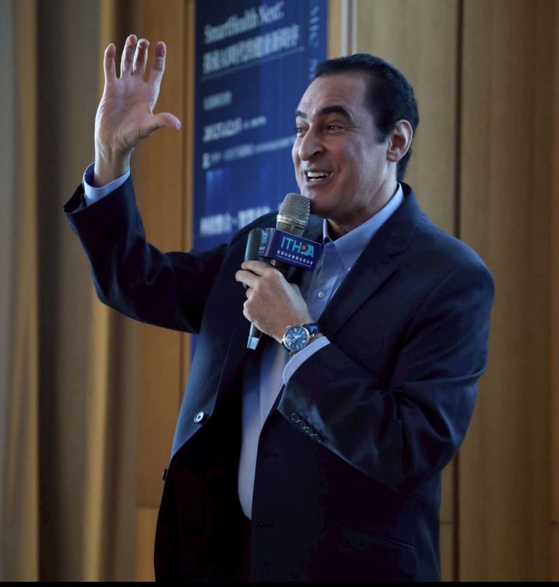 Dr. Nassef speaking with a microphone, one hand raised